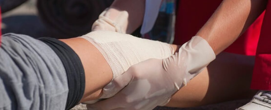 Paramedic treating a knee injury with a bandage